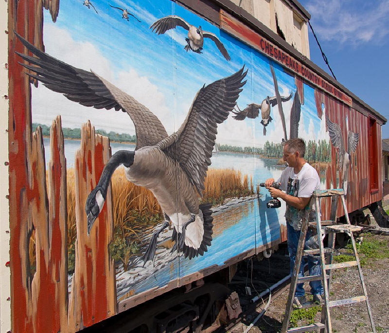 Mural side of J. M. Clayton Seafood, overlooking Cambridge Creek, portrays The Watermen, a great blue heron,