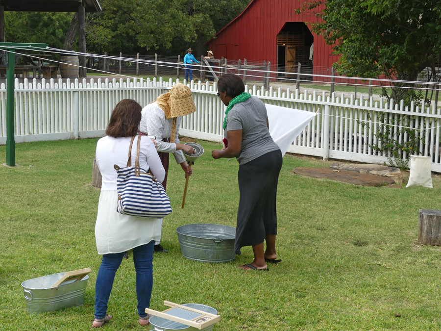 a docent shows two journalists how washing was done at Nash Farm