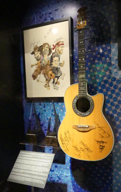 Exhibit in Johnny Cash museumof guitar and cartoon of Highwaymen