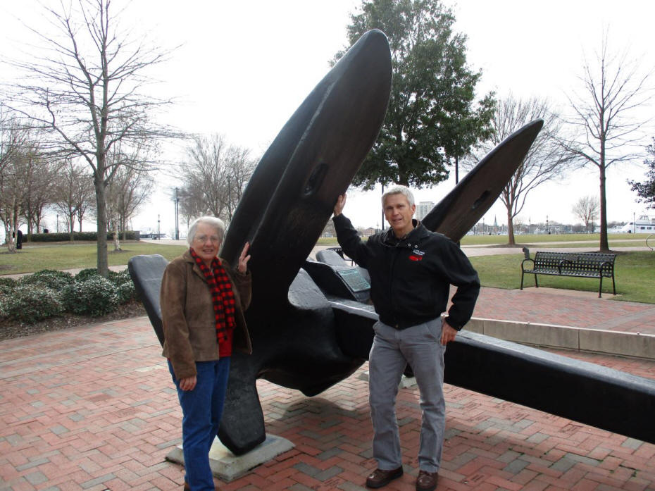 Man and woman standing by large anchor