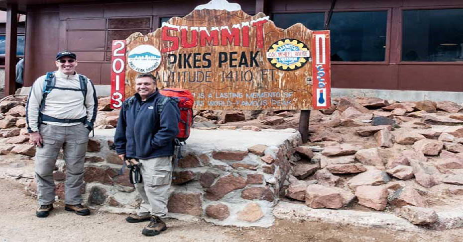 Two hikers posing at Summit Sign on Pikes Peak