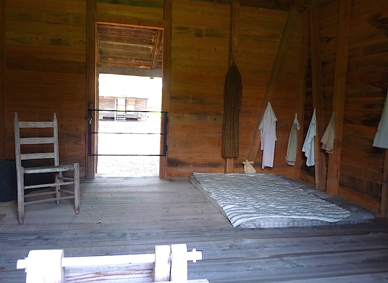 louisiana slave cabin interior with matteress on floor, chair and pegs to hang clothes