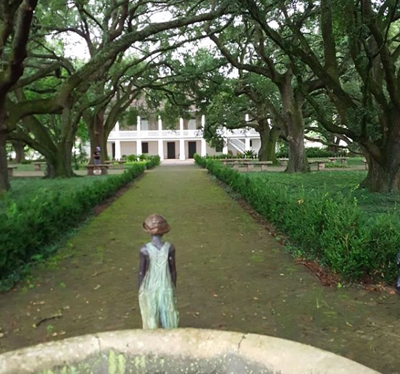 sculpture of slave chile lookng down roadway at plantation manor