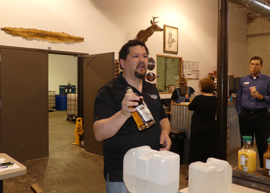 Chuck, Raymond's son, holding a bottle of TazaRay and explains why their moonshine is so unique and special.