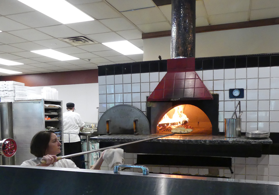 chef puts oizza in oven
