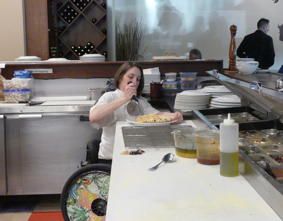 chef in wheelchair prepares pizza