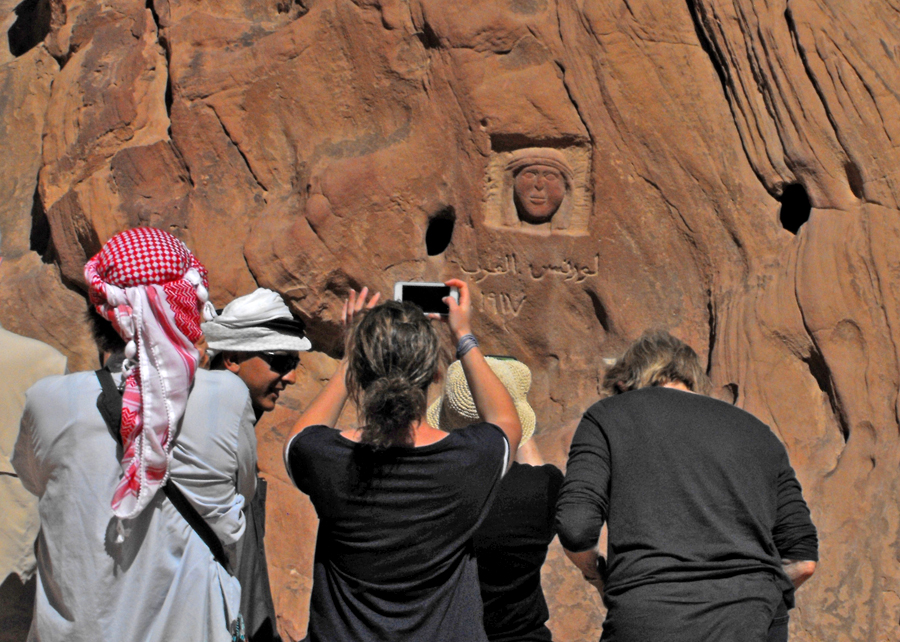 Visitors photograph carving of Lawrence of Arabia's face in Wadi Rum